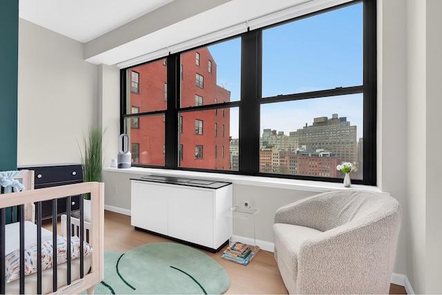 bedroom featuring wood finished floors, baseboards, and a city view