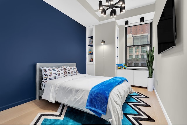 bedroom featuring wood finished floors, a chandelier, and baseboards