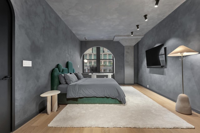 bedroom with arched walkways and wood finished floors