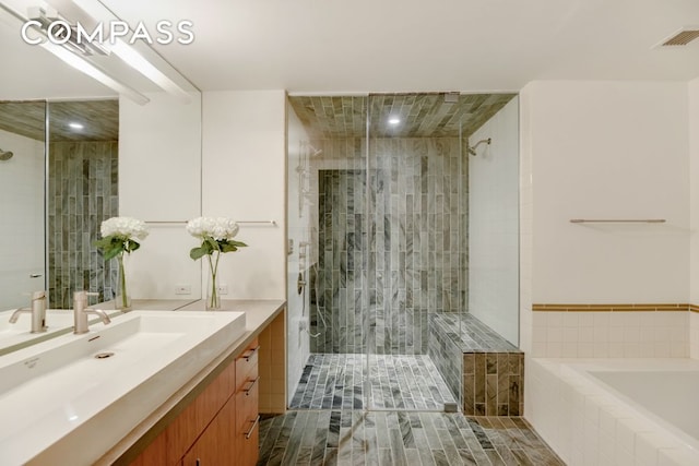 bathroom with a shower stall, vanity, tiled tub, and recessed lighting