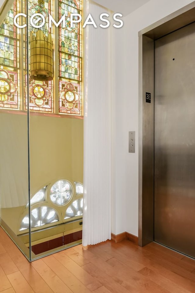 elevator featuring wood finished floors and baseboards