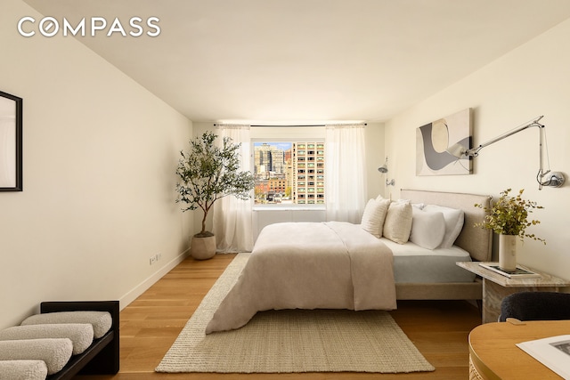 166 E 63rd St Unit 11Bc, New York City, NY 10065 - bedroom featuring wood finished floors, baseboards, and a city view