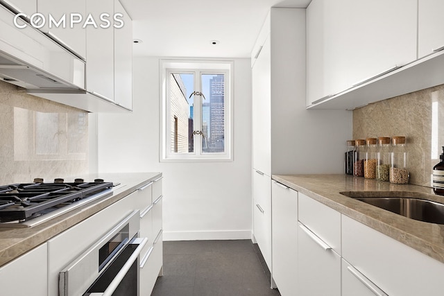 166 E 63rd St Unit 11Bc, New York City, NY 10065 - kitchen with appliances with stainless steel finishes, tasteful backsplash, white cabinets, and baseboards