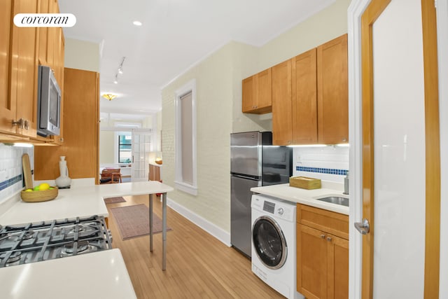 330 W 17th St Unit 2E, New York City, NY 10011 - kitchen with washer / clothes dryer, appliances with stainless steel finishes, light wood-style floors, decorative backsplash, and light countertops