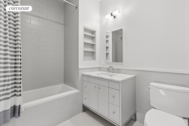 bathroom with wainscoting, vanity, toilet, tile patterned floors, and tiled shower / bath combo