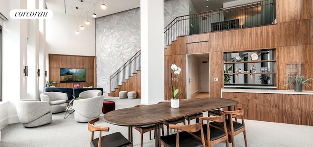 carpeted dining area with a high ceiling and stairway