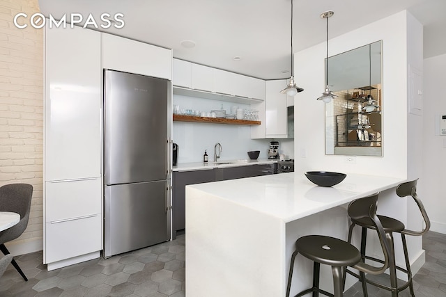 49 E 12th St Unit 2C, New York City, NY 10003 - kitchen with stainless steel refrigerator, open shelves, a breakfast bar, white cabinets, and light countertops