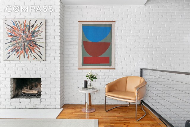 49 E 12th St Unit 2C, New York City, NY 10003 - living area with wood finished floors, a brick fireplace, and brick wall