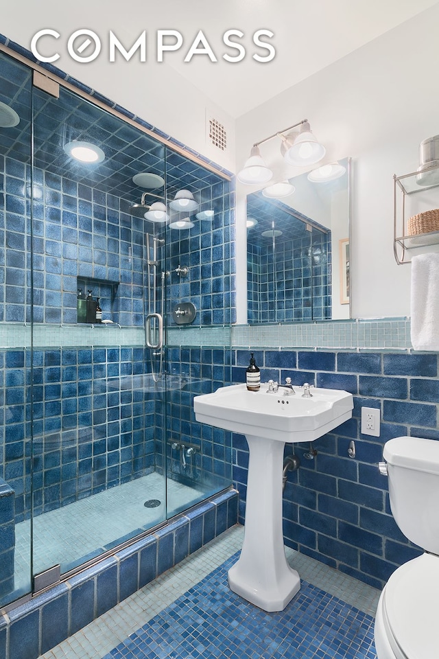 full bath with tile patterned floors, toilet, and a shower stall