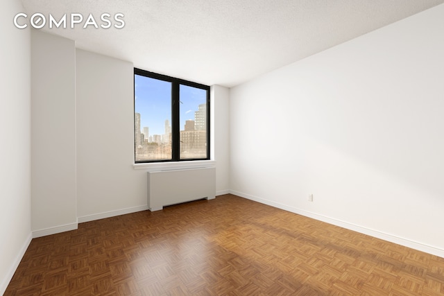 spare room with baseboards, radiator, and a skyline view