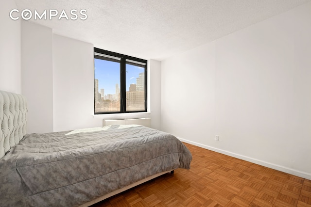 bedroom with baseboards, a textured ceiling, and a city view