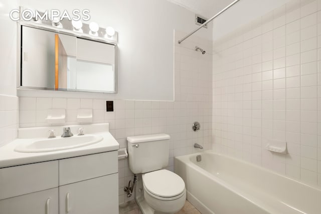 full bathroom with shower / tub combination, toilet, vanity, and tile walls