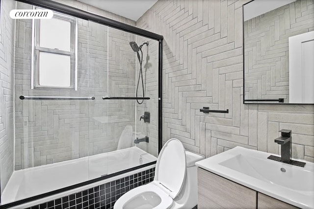 full bath with a sink, tile walls, toilet, and tiled shower