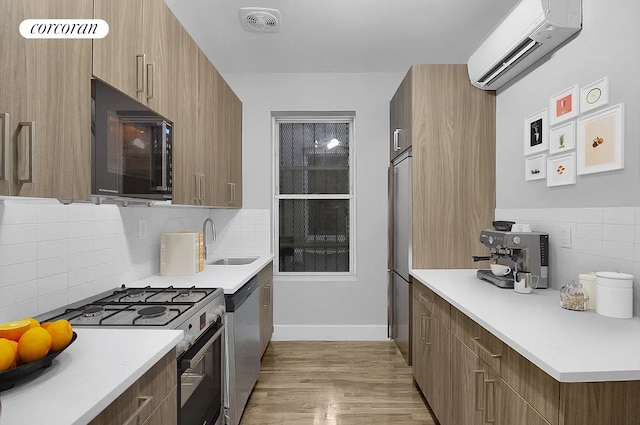 kitchen featuring a sink, light wood-style flooring, stainless steel appliances, a wall unit AC, and modern cabinets