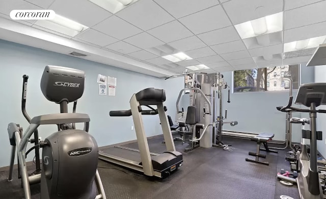 workout area with baseboards, visible vents, and a drop ceiling