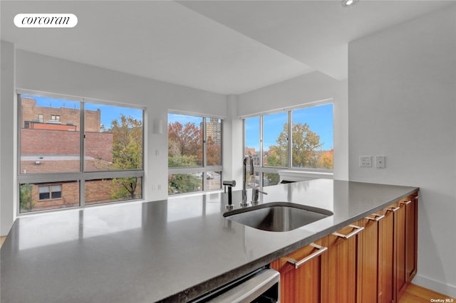 kitchen featuring brown cabinetry, a sink, a wealth of natural light, and visible vents
