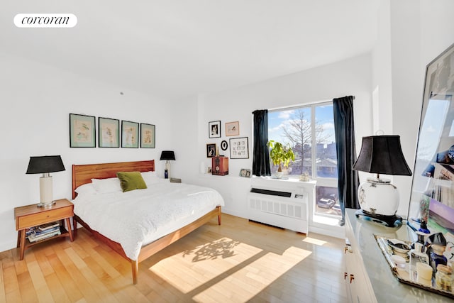 bedroom with light wood-style floors, radiator, and visible vents