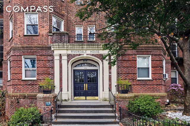 doorway to property featuring brick siding, fence, and french doors