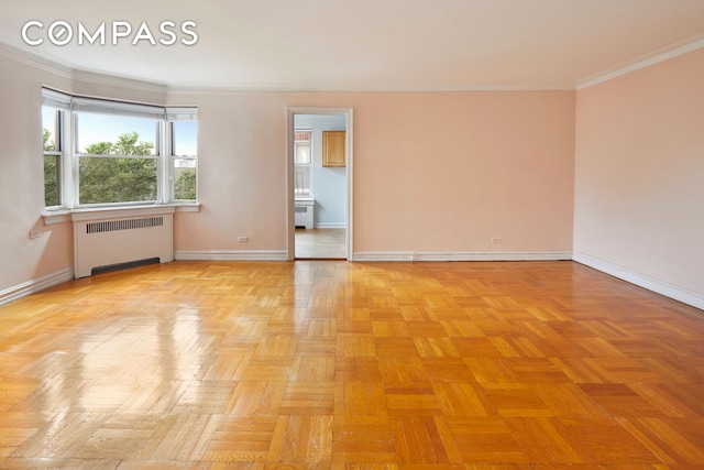 spare room with crown molding, baseboards, and radiator heating unit