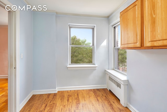 unfurnished room with baseboards, ornamental molding, radiator heating unit, and light wood-style floors