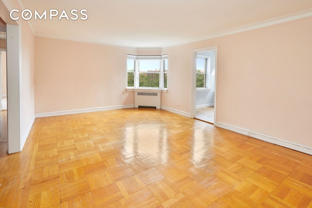 spare room featuring crown molding, radiator, and baseboards