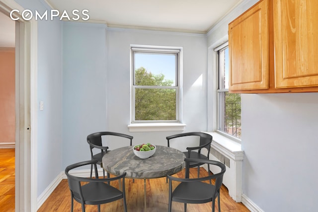 dining room with crown molding, baseboards, radiator heating unit, and light wood-style floors