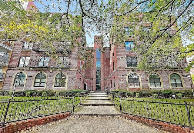 view of front of home featuring brick siding, a fenced front yard, and a front lawn