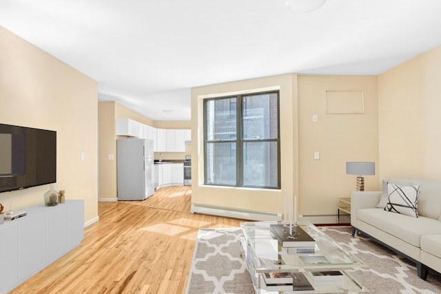 living area with light wood-style floors, baseboards, and a baseboard heating unit