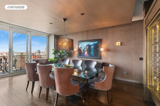 dining space featuring visible vents, a view of city, wood finished floors, baseboards, and expansive windows