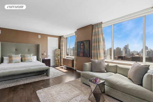 201 E 80th St Unit 23A, New York City, NY 10028 - bedroom with multiple windows, wood-type flooring, a view of skyline, and baseboards