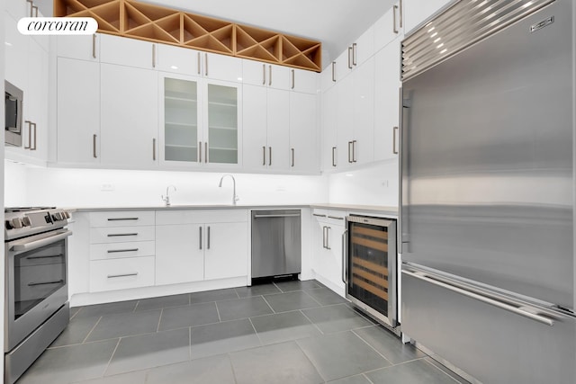 kitchen with light countertops, beverage cooler, appliances with stainless steel finishes, and dark tile patterned floors
