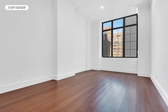 unfurnished room featuring recessed lighting, baseboards, dark wood finished floors, and ornamental molding