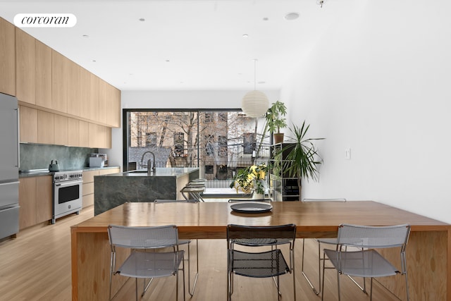kitchen with a center island with sink, high end stainless steel range oven, light wood-style flooring, and modern cabinets