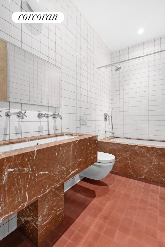 bathroom with tile walls, tiled shower / bath, tile patterned floors, and toilet