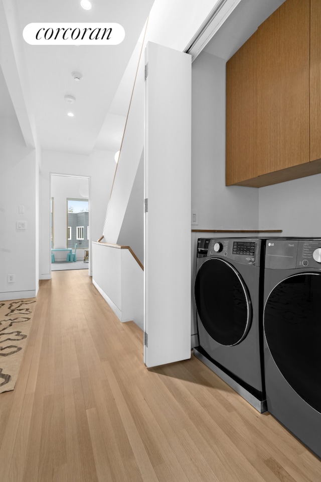 laundry room featuring separate washer and dryer, light wood-style flooring, and cabinet space