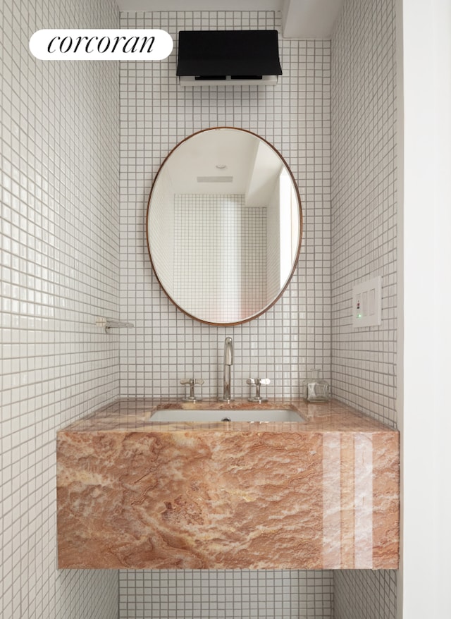 bathroom featuring a sink and tile walls