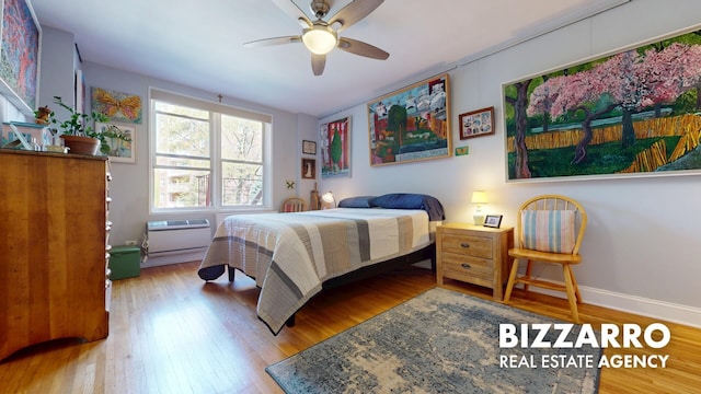 bedroom with baseboards, a ceiling fan, an AC wall unit, and wood finished floors