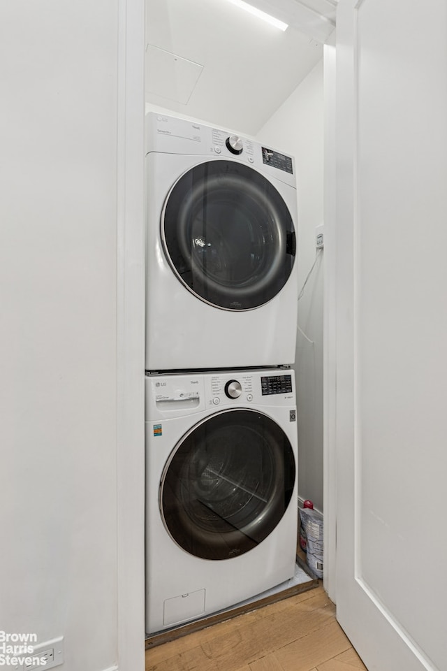 laundry room featuring stacked washer / dryer and light wood-style flooring