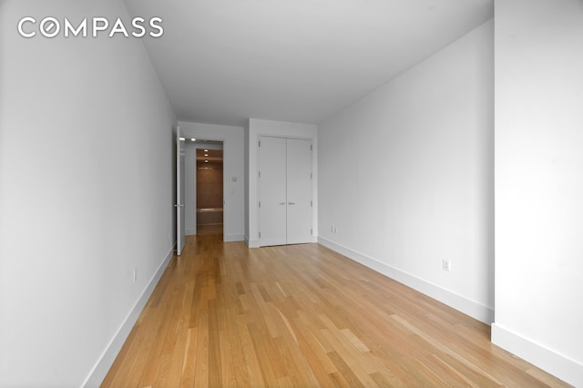unfurnished bedroom featuring baseboards, a closet, and light wood-type flooring