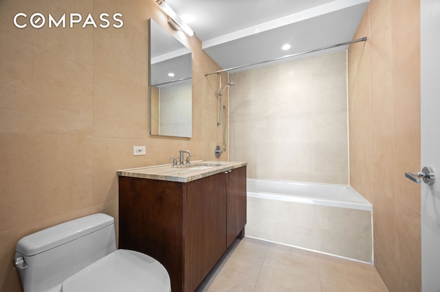 full bath with vanity, toilet, tile walls, tile patterned floors, and tiled shower / bath combo