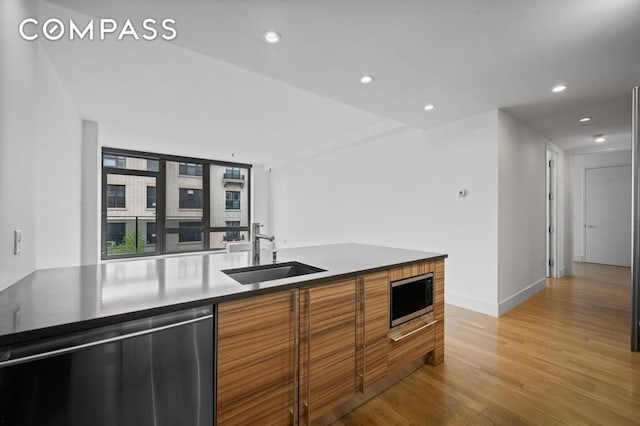 kitchen featuring brown cabinets, appliances with stainless steel finishes, a sink, light wood-style flooring, and recessed lighting