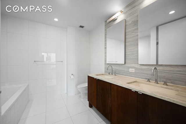 bathroom with tile patterned flooring, a sink, toilet, and tile walls