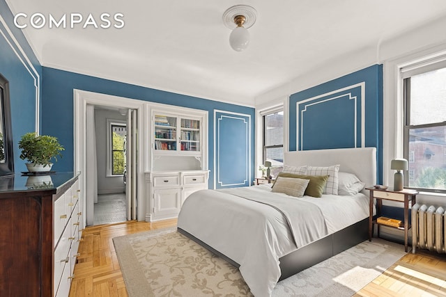 bedroom with radiator heating unit and multiple windows