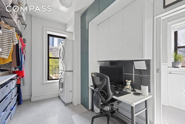 office with baseboards and stacked washer and dryer