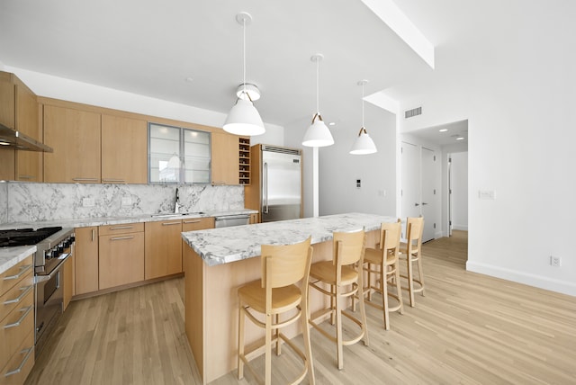 121 W 19th St Unit 9E, New York City, NY 10011 - kitchen featuring high end appliances, light wood finished floors, backsplash, and a breakfast bar