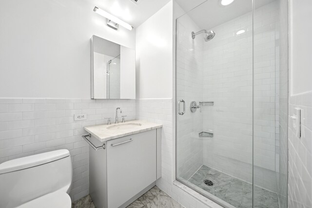 121 W 19th St Unit 9E, New York City, NY 10011 - bathroom with tile walls, vanity, a shower stall, marble finish flooring, and a wainscoted wall