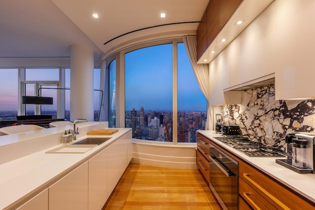 kitchen featuring stainless steel gas cooktop, wall oven, modern cabinets, light countertops, and white cabinetry