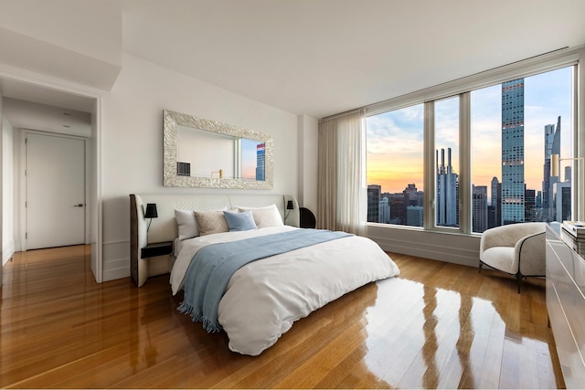 bedroom with baseboards, a view of city, and wood finished floors