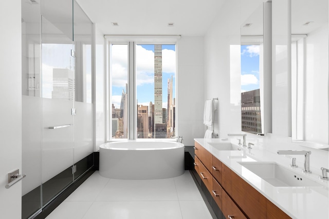 full bathroom featuring double vanity, a sink, a freestanding bath, and tile patterned floors