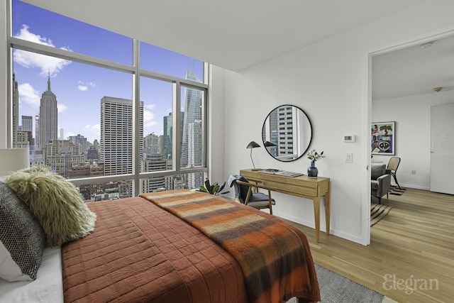 18 W 48th St Phd, Phd, New York City, NY 10036 - bedroom featuring expansive windows, a view of city, baseboards, and wood finished floors